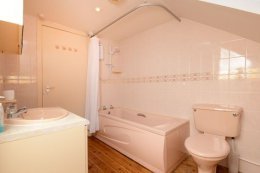 The upstairs bathroom with over-bath shower, toilet and sink.